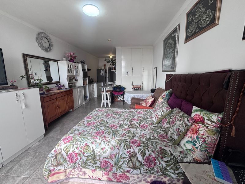 Open-plan living and sleeping area featuring tiled flooring, built-in cabinetry, and integrated storage cupboards in a retirement village setting.