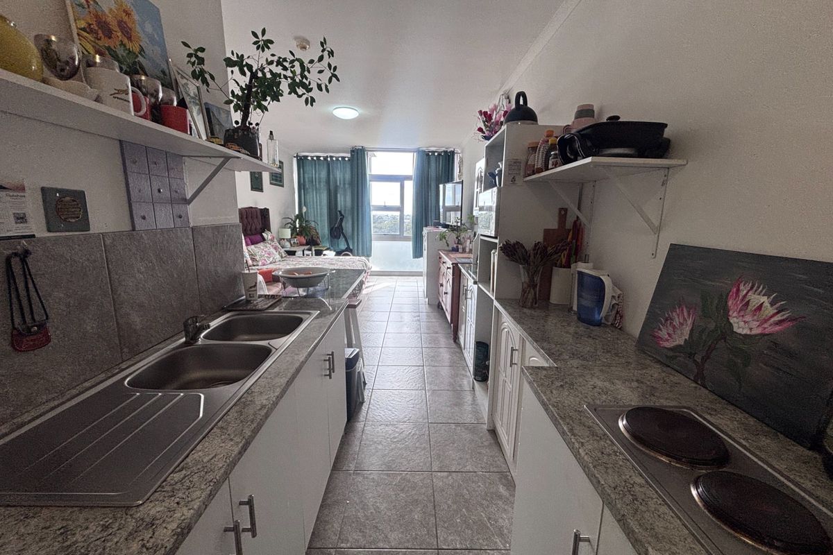 Open-plan kitchen and living area featuring tiled flooring, built-in cabinetry with laminate countertops, and an integrated electric hob.