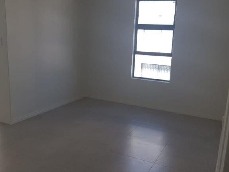An empty bedroom featuring neutral tiled flooring and a central ceiling light fixture, providing a blank canvas for interior design.