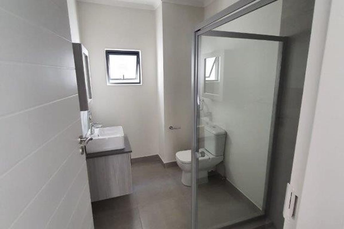 Modern bathroom featuring a vessel sink vanity, a glass-enclosed shower, and a toilet with neutral floor tiling.