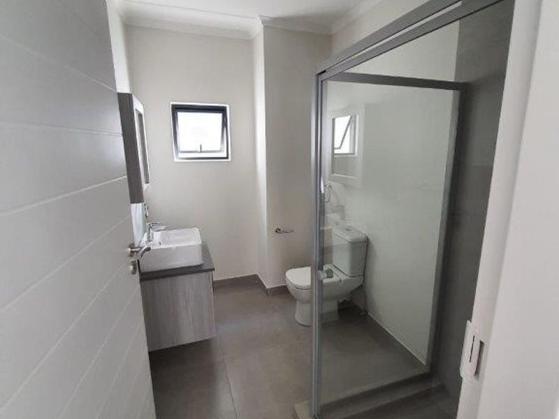 Modern bathroom featuring a vessel sink vanity, a glass-enclosed shower, and a toilet with neutral floor tiling.