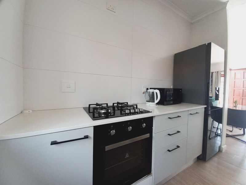 Modern kitchen featuring light grey cabinetry, a gas hob, built-in oven, and clean tiled splashback, offering a functional and contemporary cooking space.