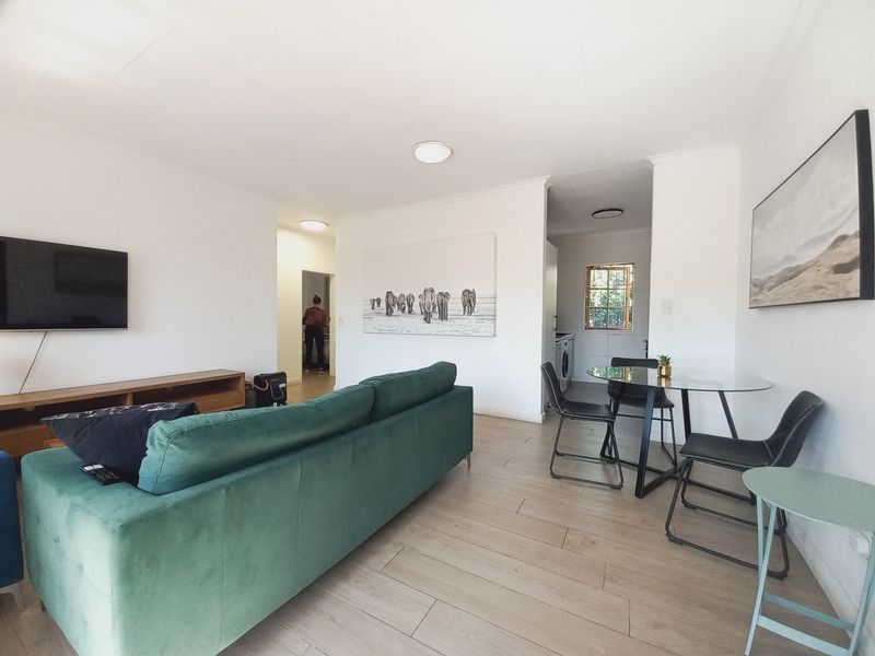 An open-plan living and dining area featuring light wood-look tile flooring and neutral walls, providing a bright and functional space.