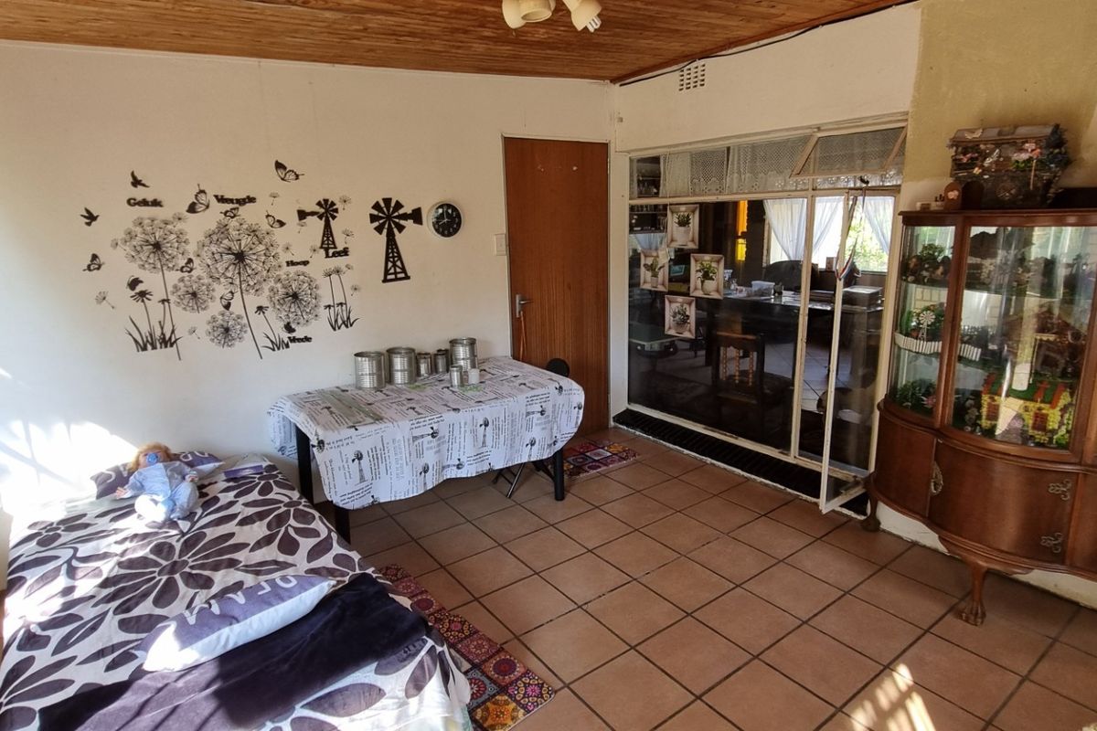 A living area featuring tiled flooring and a timber ceiling, with a sliding glass door providing access to an adjacent space.