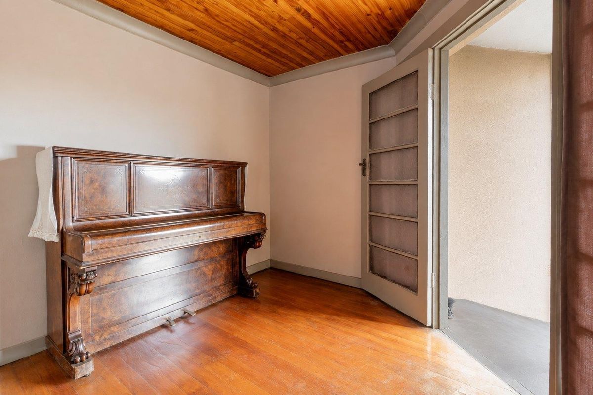 A bedroom featuring warm timber ceiling paneling, polished hardwood flooring, and a glass-paneled door providing access to an outdoor area.