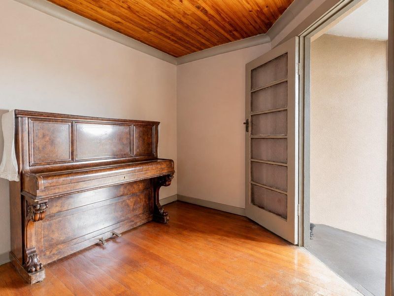 A bedroom featuring warm timber ceiling paneling, polished hardwood flooring, and a glass-paneled door providing access to an outdoor area.