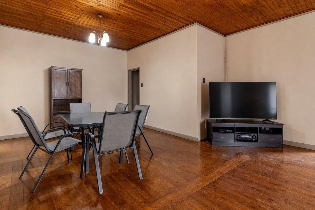 A living area featuring warm timber ceilings and original hardwood flooring, offering a classic foundation for modern interior updates.