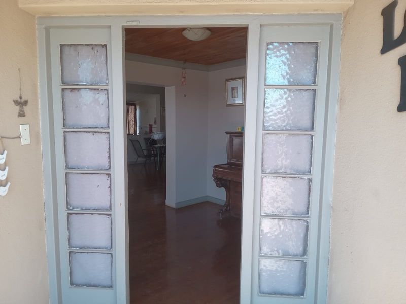Entrance area featuring a timber ceiling, hardwood flooring, and double doors with textured glass sidelights leading into the main living space.