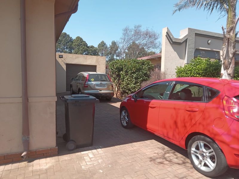 A view of the paved driveway leading to a garage, showing the exterior facade of the property.