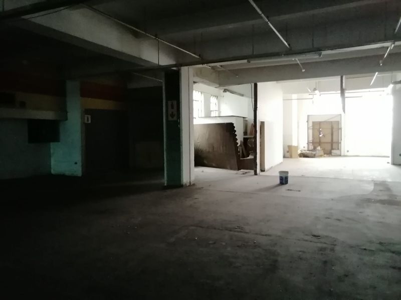 An expansive, open-plan commercial utility space featuring exposed concrete ceilings, structural columns, and industrial flooring, suitable for warehouse or workshop conversion.