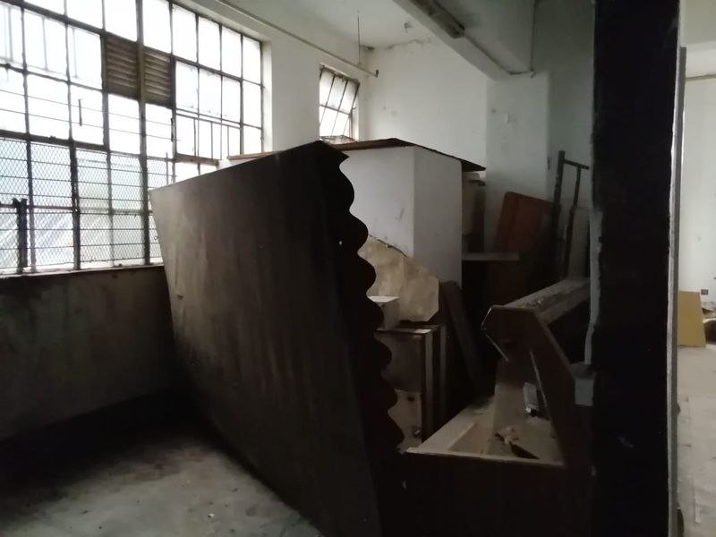 An industrial utility space featuring large steel-framed windows and concrete flooring, currently in need of significant renovation and refurbishment.