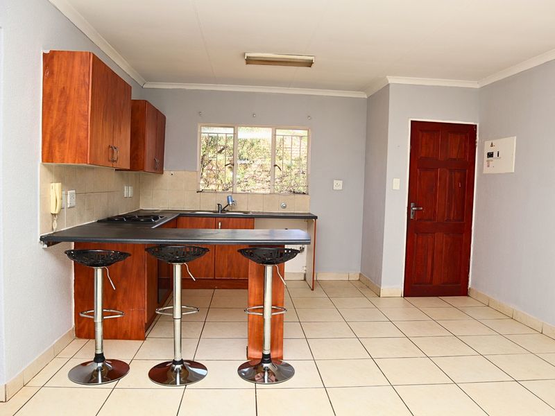 Functional kitchen featuring laminate cabinetry, a breakfast bar, built-in hob, and tiled flooring, offering a practical layout for daily meal preparation.