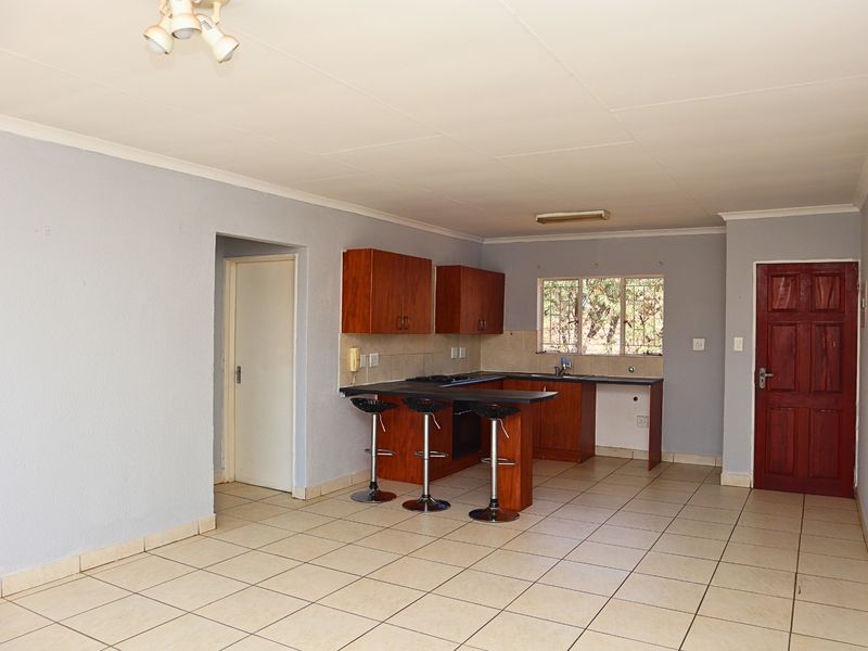 Open plan kitchen and living area featuring tiled flooring, wooden cabinetry, built-in oven, and a breakfast counter.
