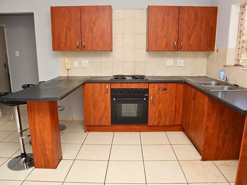 A functional kitchen featuring wood-look cabinetry, a built-in oven and hob, tiled backsplash, and a convenient breakfast bar counter.