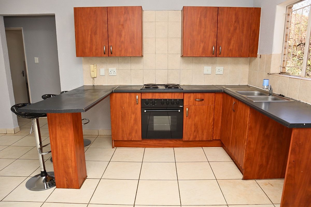 A functional kitchen featuring wood-look cabinetry, a built-in oven and hob, tiled backsplash, and a convenient breakfast bar counter.