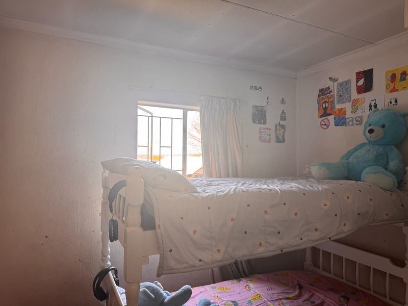 A bedroom featuring a window with security bars and coved ceiling detailing, requiring cosmetic updates to the wall and ceiling finishes.
