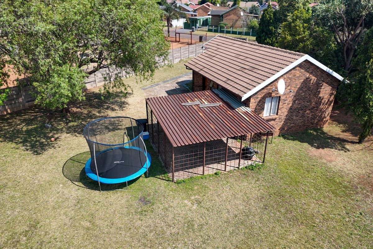 Aerial view of the property showing the rear brick facade, tiled roof, and a covered patio area with weathered roofing.