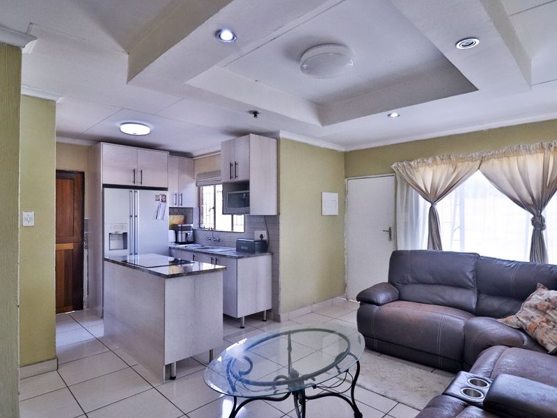 Open-plan living area featuring a functional kitchen with built-in cabinetry, a central island, and tiled flooring throughout the combined space.