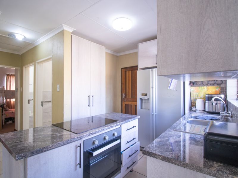 Functional kitchen featuring built-in oven, electric hob, double sink, and ample cabinetry with laminate countertops.