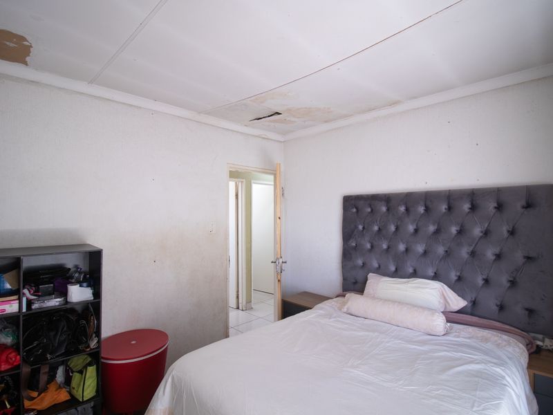 A bedroom featuring visible ceiling damage and wall staining, requiring maintenance and cosmetic updates to improve the overall condition of the space.