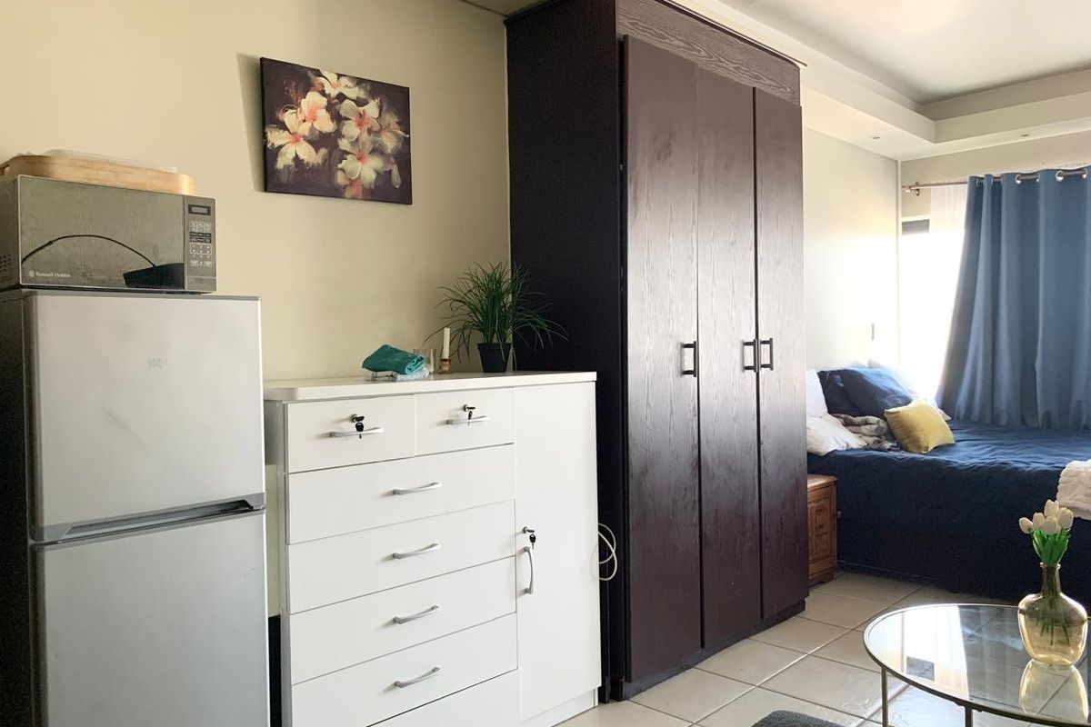 A bedroom featuring tiled flooring, recessed ceiling lighting, and a large dark wood built-in wardrobe.
