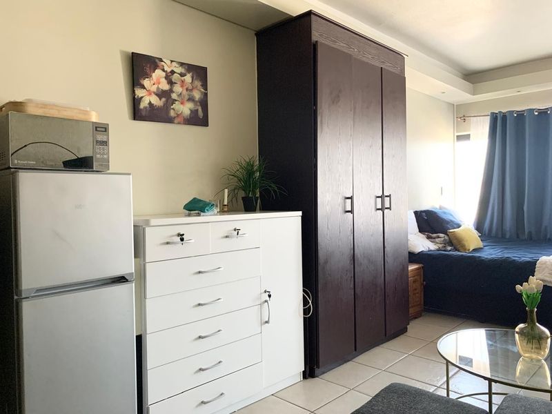 A bedroom featuring tiled flooring, recessed ceiling lighting, and a large dark wood built-in wardrobe.