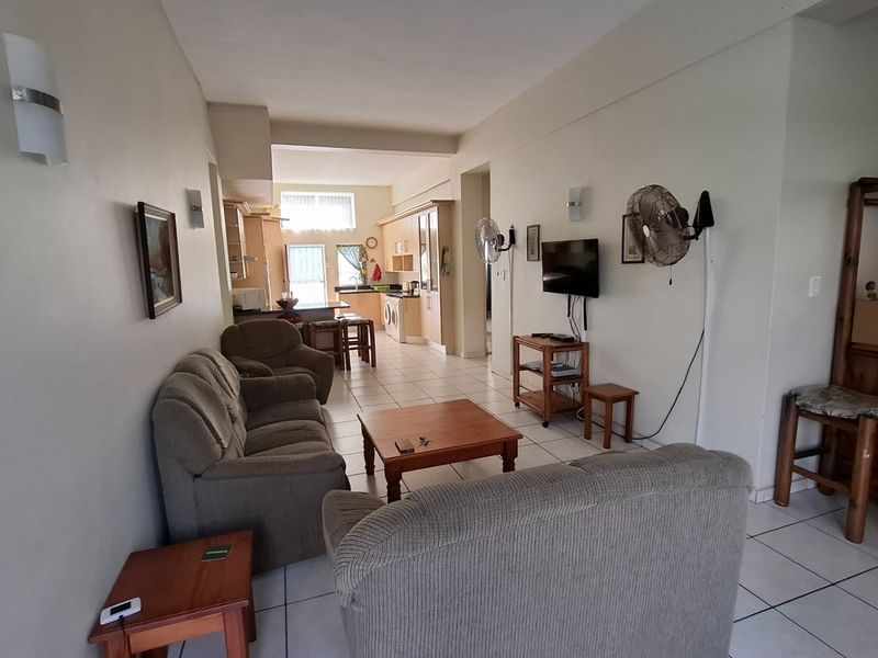 Open-plan living and kitchen area featuring tiled flooring and functional built-in cabinetry, offering a versatile space for relaxation and dining.