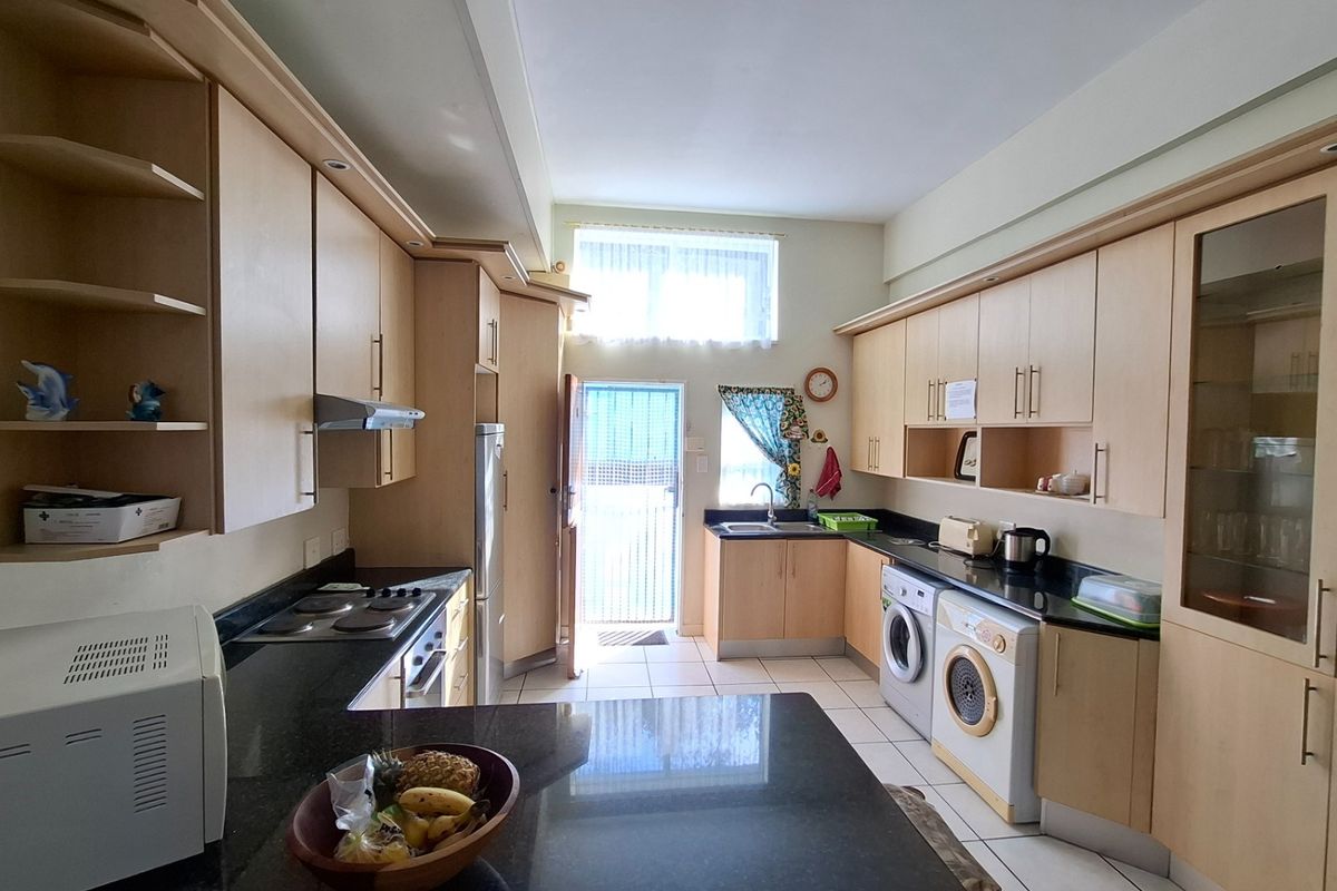 Functional kitchen featuring extensive built-in cabinetry, granite countertops, integrated laundry facilities, and direct access to an exterior door.