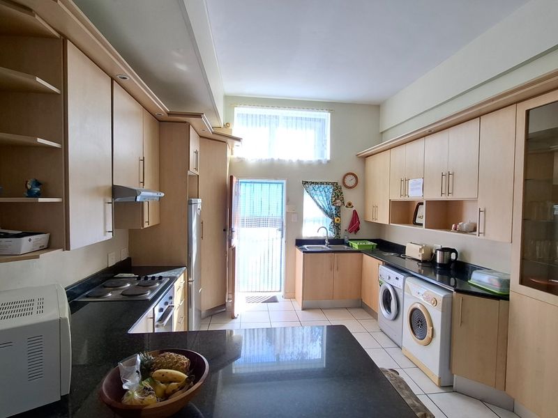 Functional kitchen featuring extensive built-in cabinetry, granite countertops, integrated laundry facilities, and direct access to an exterior door.