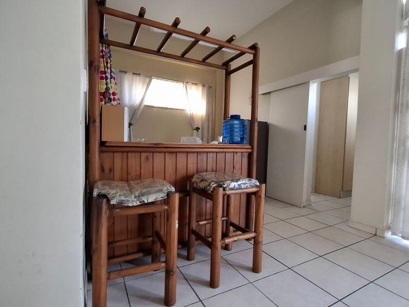 A dedicated bar area featuring a built-in wooden counter and tiled flooring, providing a functional space for entertaining within the apartment.