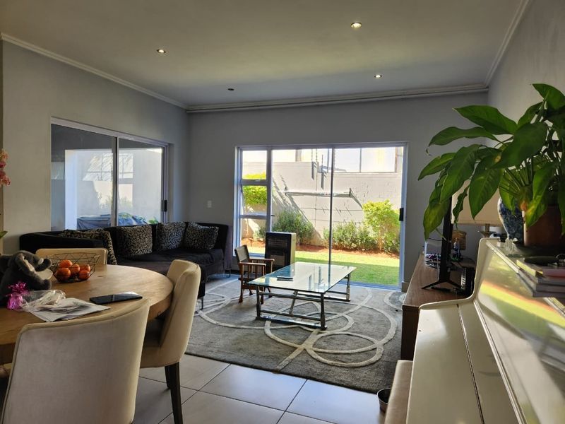 Open-plan living and dining area featuring tiled floors, recessed lighting, and large sliding glass doors providing direct access to the rear garden.