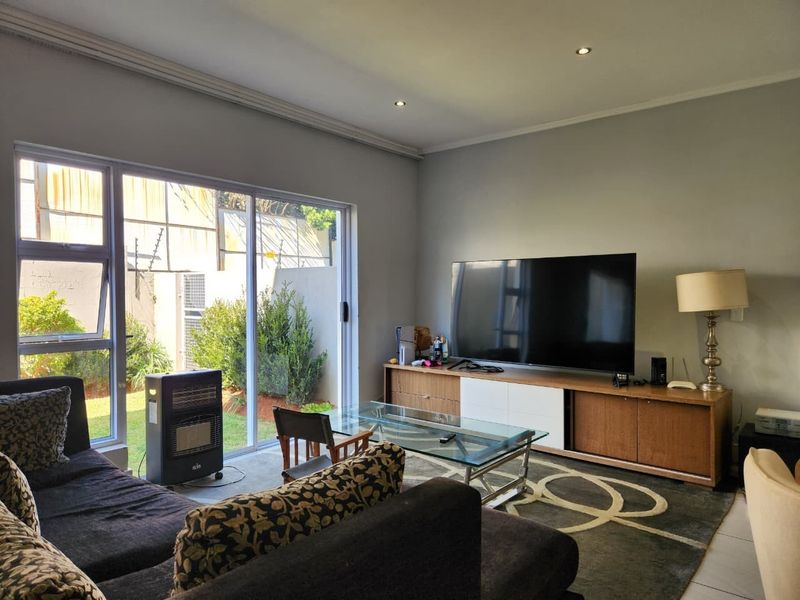 A bright living room featuring large sliding glass doors that provide natural light and direct access to the outdoor garden area.
