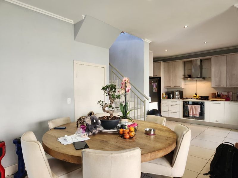 Open-plan living and dining area featuring a modern kitchen with built-in cabinetry, integrated appliances, and a staircase leading to the upper level.