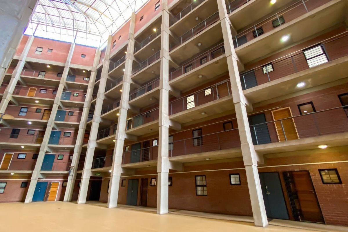 A view of the apartment complex atrium featuring a large skylight, multi-level walkways, and exposed brick architecture.