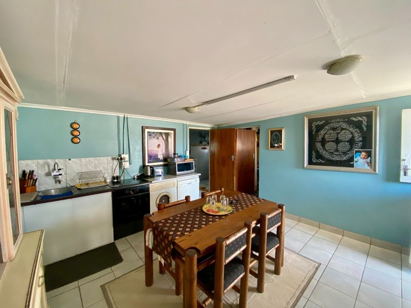 Open plan kitchen and dining area featuring tiled flooring, built-in cabinetry, and integrated oven, requiring cosmetic updates to the ceiling and finishes.