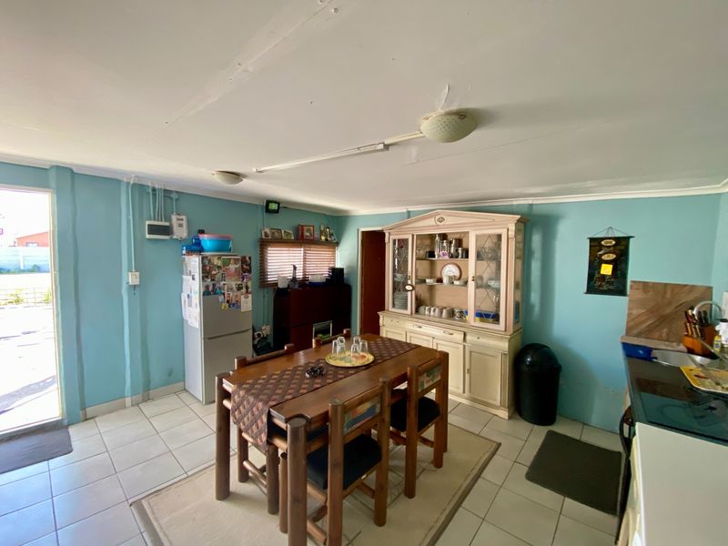Open plan living and dining area featuring tiled flooring and direct access to the exterior, with visible surface-mounted electrical conduits.