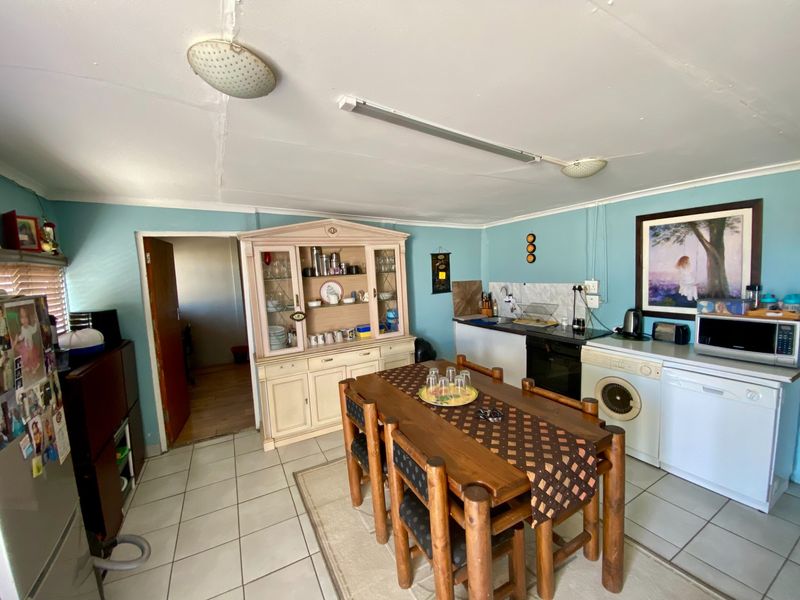 A functional kitchen area featuring tiled flooring, built-in cabinetry, and integrated appliances, currently serving as a combined kitchen and dining space.