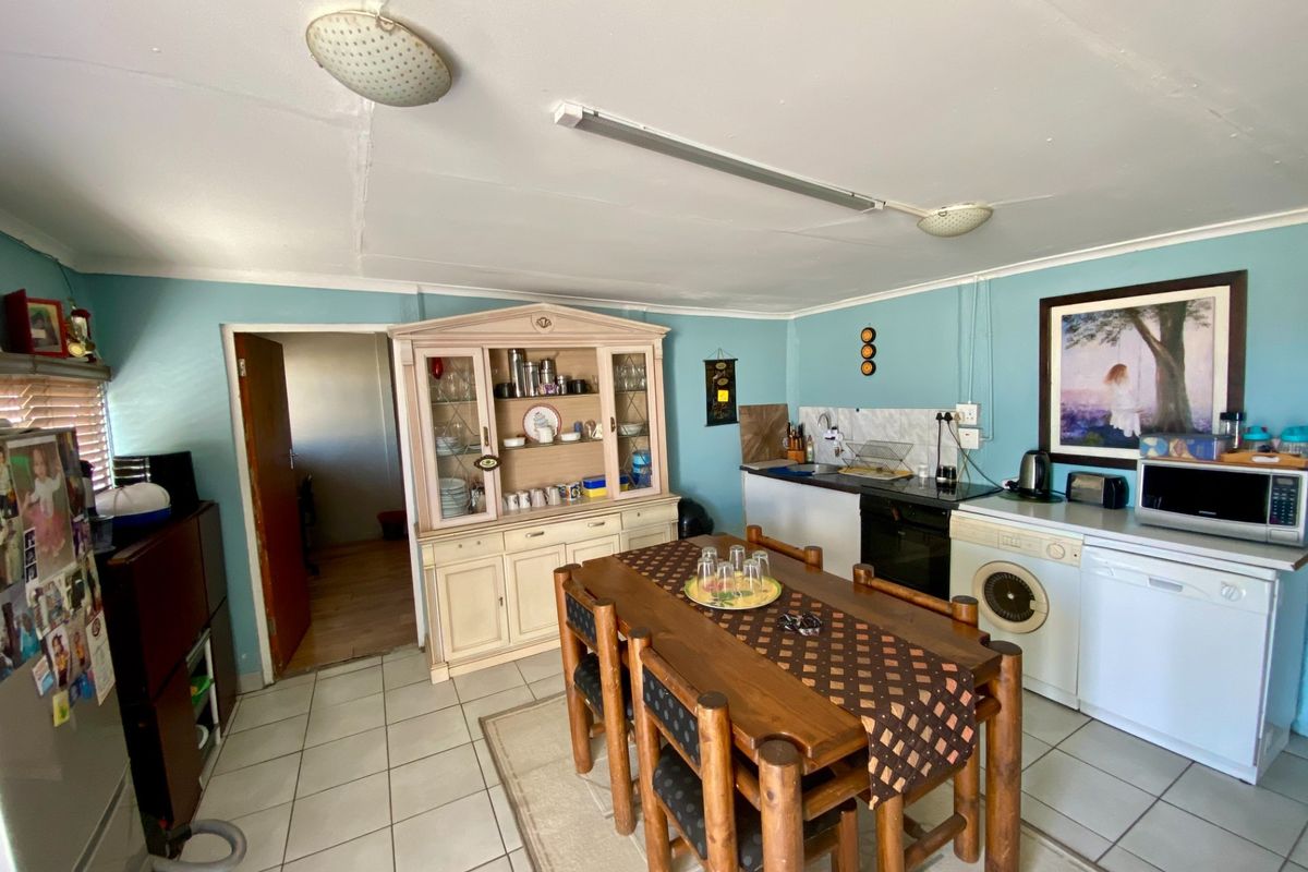 A functional kitchen area featuring tiled flooring, built-in cabinetry, and integrated appliances, currently serving as a combined kitchen and dining space.