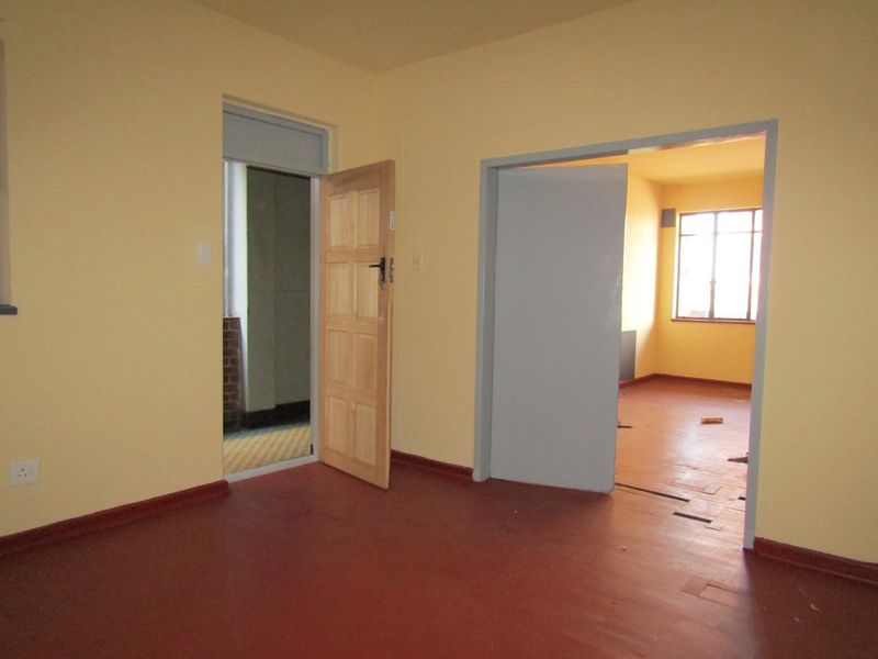 An empty, dated living area featuring painted floors and simple interior doors, offering a blank canvas for renovation and modernization.