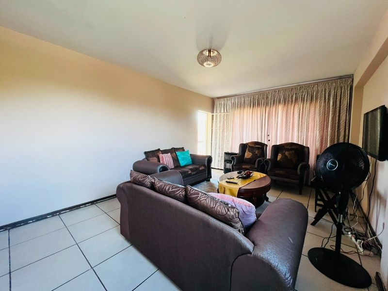 A spacious living room featuring tiled flooring and a large sliding glass door that provides access to the outdoor area.