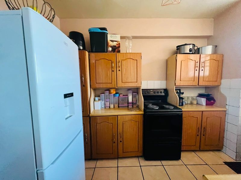 A functional kitchen featuring wooden cabinetry, laminate countertops, tiled backsplash, and ceramic floor tiles, providing a practical workspace for daily cooking.