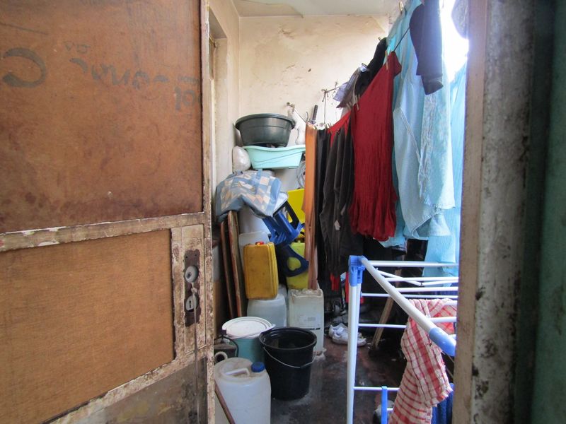 A small utility or laundry area showing signs of significant wear and tear, requiring maintenance and refurbishment of wall and ceiling finishes.