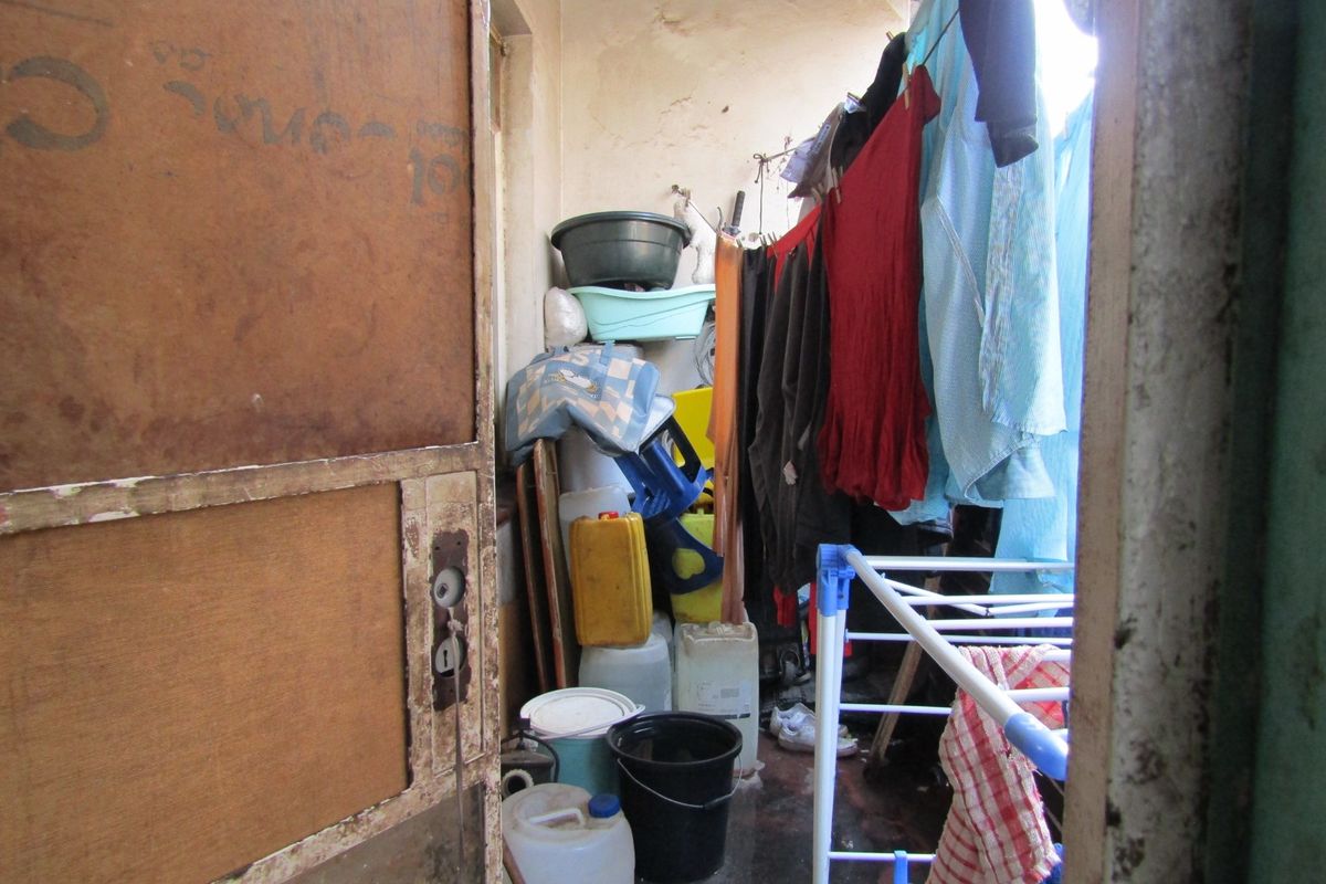 A small utility or laundry area showing signs of significant wear and tear, requiring maintenance and refurbishment of wall and ceiling finishes.