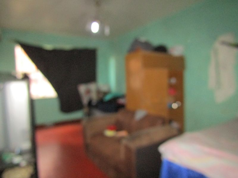 A blurry interior view of a bedroom space with painted walls and basic flooring.