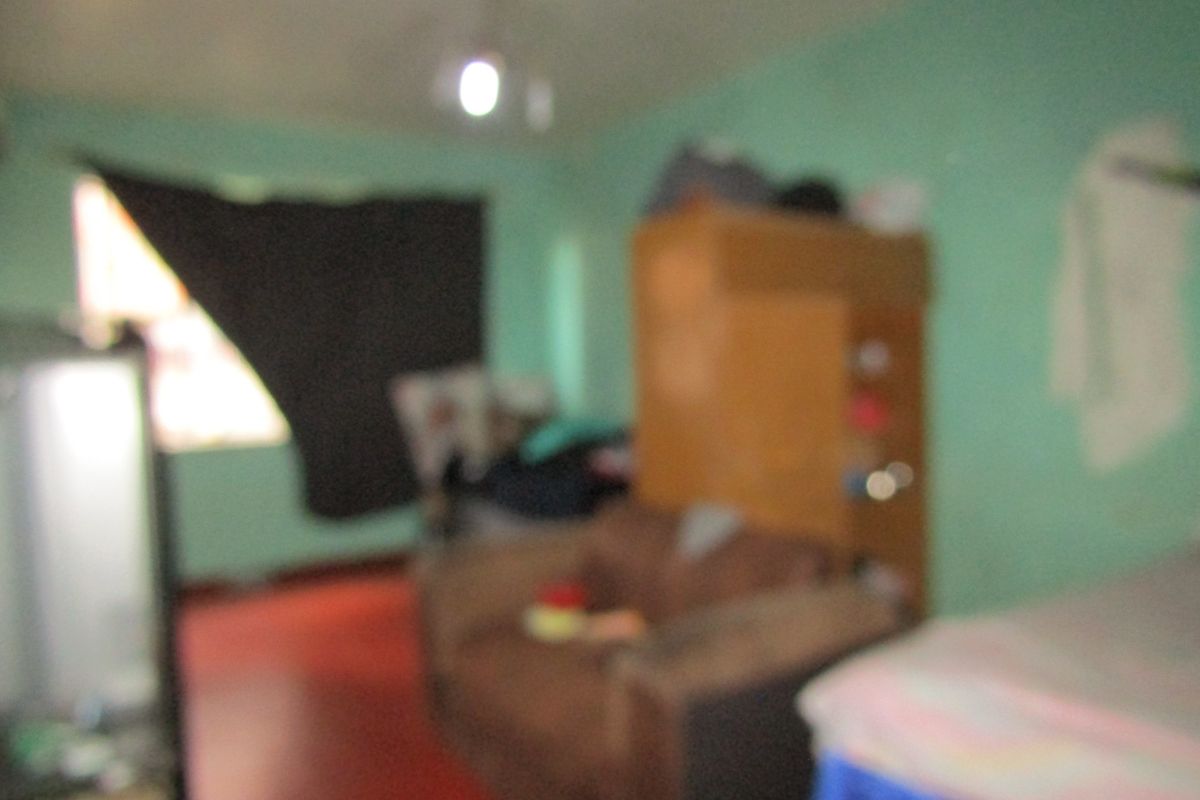 A blurry interior view of a bedroom space with painted walls and basic flooring.