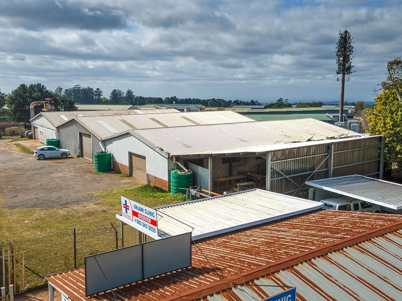 Aerial view of an industrial property featuring multiple corrugated metal warehouse structures, paved yard space, perimeter fencing, and water storage tanks.