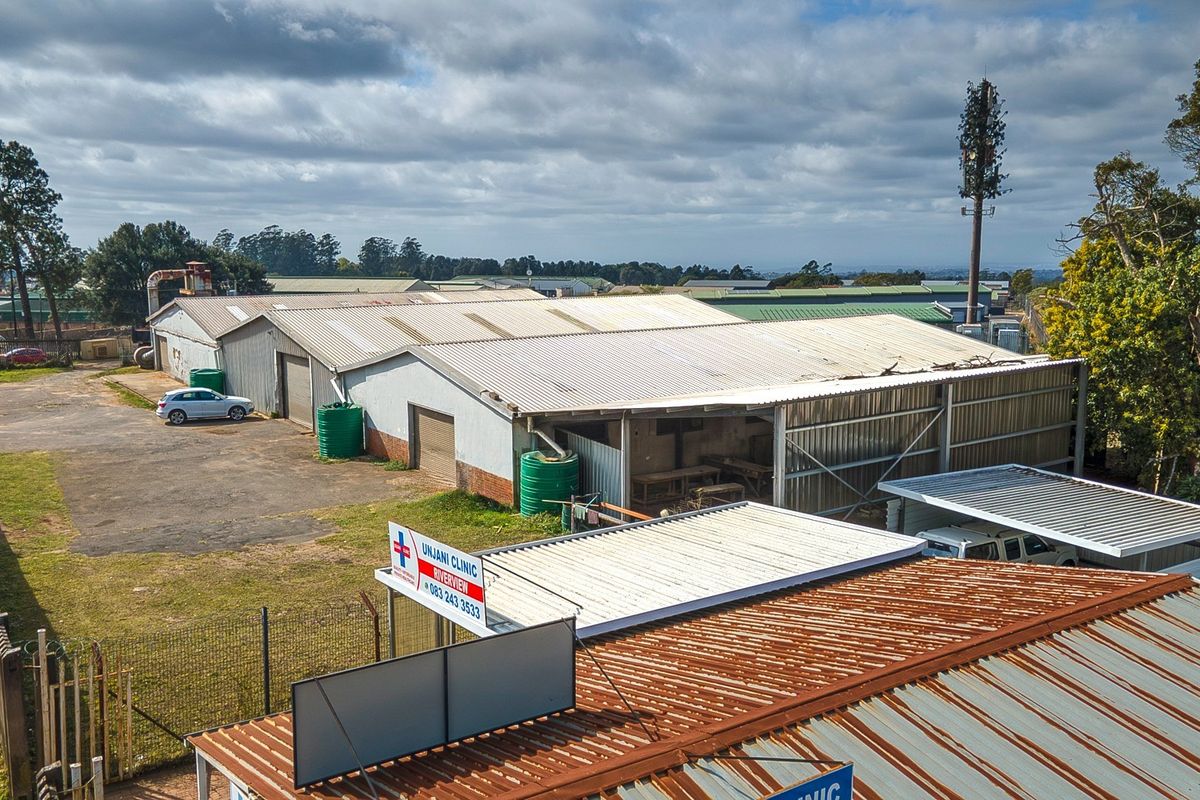 Aerial view of an industrial property featuring multiple corrugated metal warehouse structures, paved yard space, perimeter fencing, and water storage tanks.