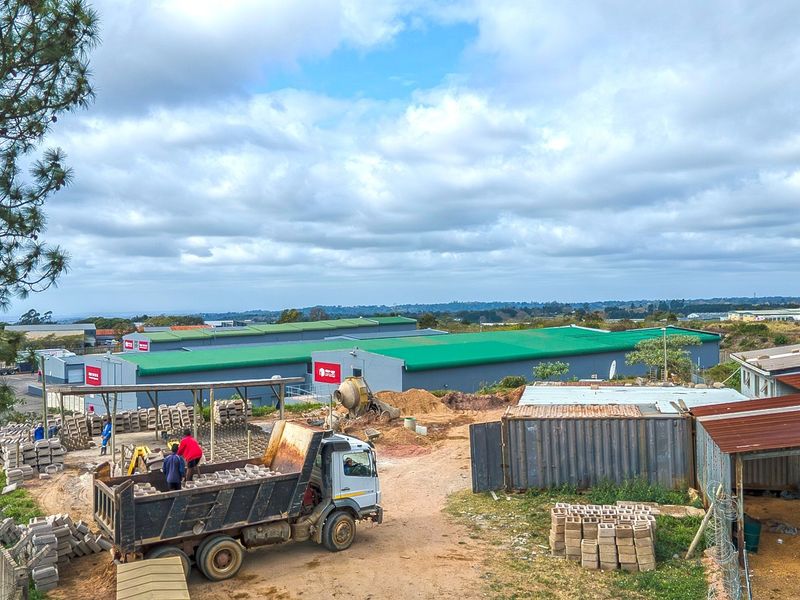 Aerial view of an industrial property featuring warehouse buildings, metal roofing, and an unpaved yard area with perimeter fencing.