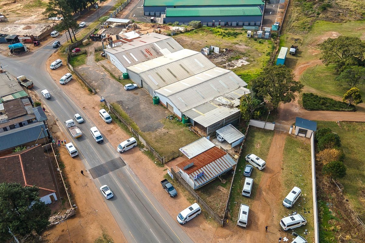 Aerial view of an industrial property featuring a large warehouse building, paved yard area, and perimeter fencing with direct street access.