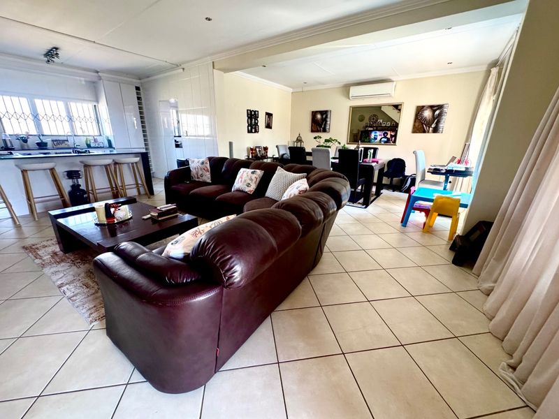 Spacious open-plan living area featuring a kitchen with island, ceramic tile flooring, and integrated air conditioning, creating a functional and connected family space.